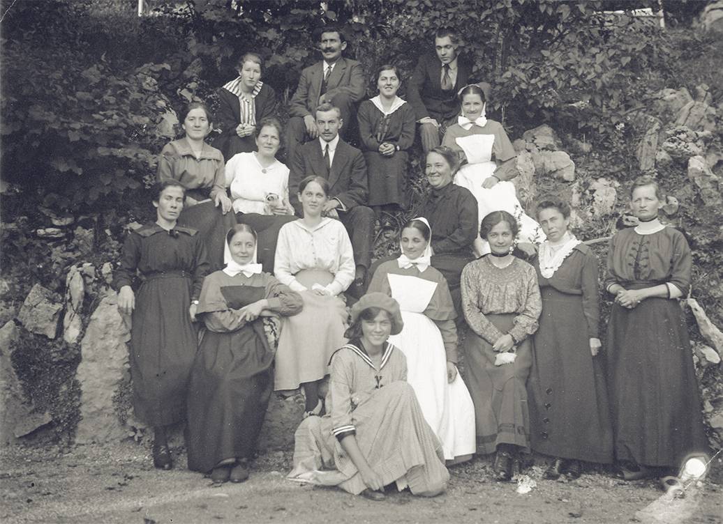 スイス、ランゲンブルックの精神病院で患者と看護師たちの一団の前で膝まづくアドリエンヌ(1918年)